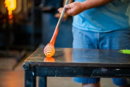 hot shop glass blowing artistry with a spun white glass over the orange molten glassの写真素材