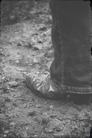 A pair of embroidered cowboy boots, scuffed from the dust and dirt, stand as a quiet testament to long days, open spaces, and the enduring spirit of the West.の写真素材