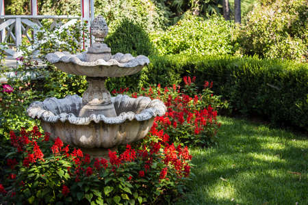 Acorn Fountain surrounded by red flowersの写真素材