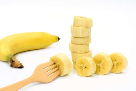 Wooden fork in a piece of banana isolate on white backgroundの写真素材