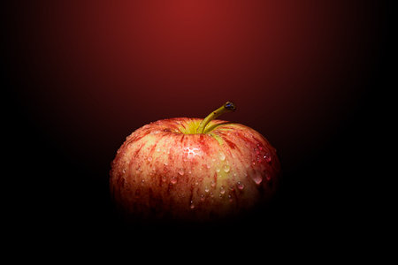 Red apples with drops of water in light and shadow on black and red background