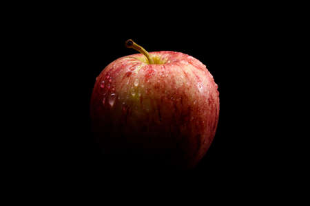 Red apple with drops of water in light and shadows on black backgroundの写真素材