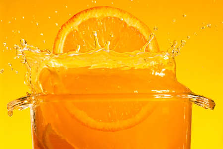 Orange slice falling into juice. Macroの写真素材