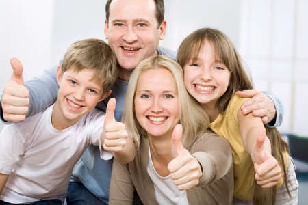 Cheerful family of four with their thumbs upの写真素材