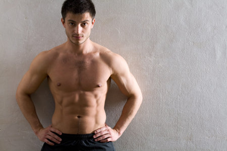 Portrait of muscular man leaning against the wall 
