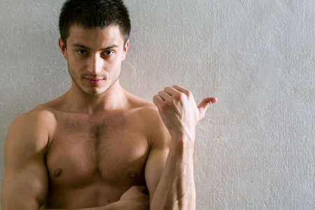 Portrait of muscular man who is pointing a finger at a gray wall
の写真素材
