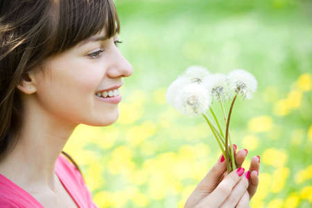 Young woman admiring dandelionsの写真素材