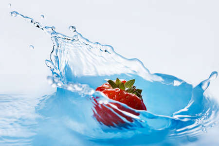 Strawberry falls deeply under water with a splashの写真素材