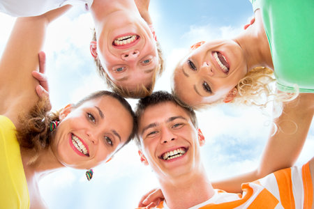 Group of happy young people in circle at beach have fun and smileの写真素材