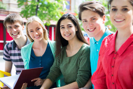 Group of university students studying, reviewing homework in parkの写真素材