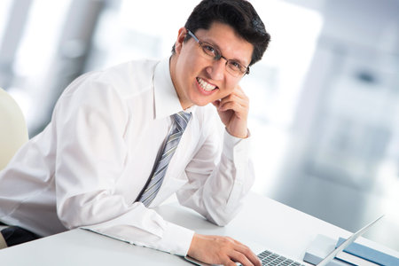 Happy business man sitting in front of laptop