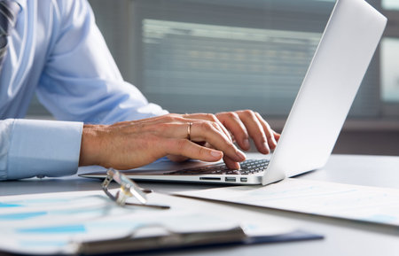 Close-up image of typing male hands at laptppの写真素材