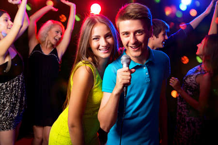 Young people singing into microphone at party Young people singing into microphone at party