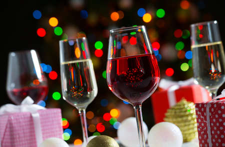 Glasses of wine and christmas gifts on the bright backgroundの写真素材
