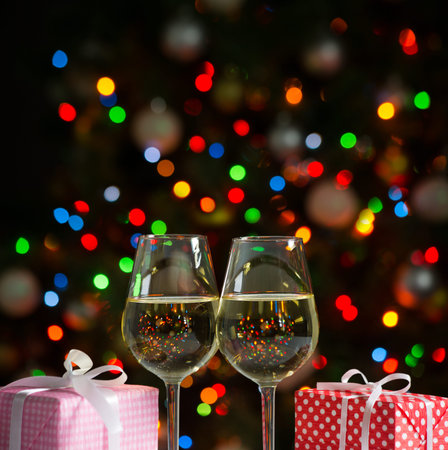 Glasses of wine and christmas gifts on the bright backgroundの写真素材