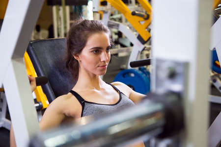 Fitness. Woman at the gym doing arms exercises on a machine