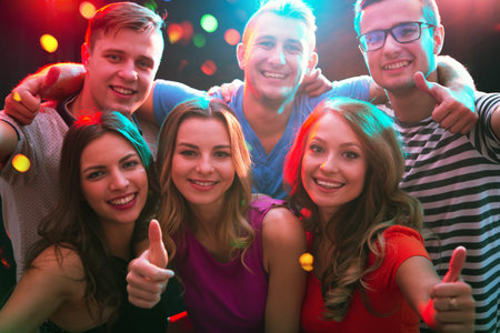 Group of happy friends posing in the night club