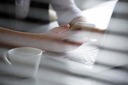 Business woman holding phone and using laptop. Online paymentの写真素材
