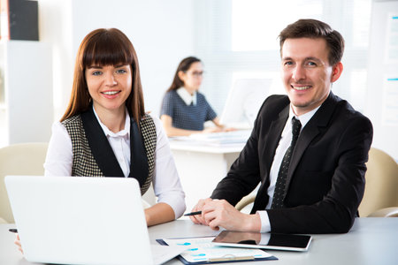 Business people are looking into the camera while working in the officeの写真素材