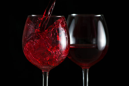 Beautiful splash of red wine in a glass on a black backgroundの写真素材