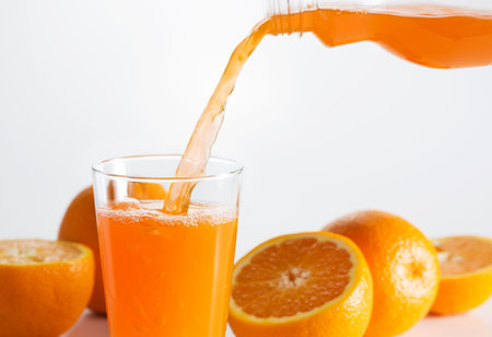 A glass of orange juice creating a splash among orangesの写真素材