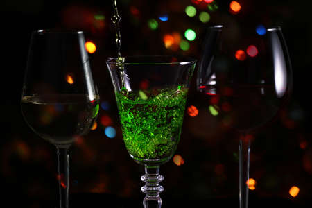 Beautiful splash of green cocktail on the background of festive lightsの写真素材
