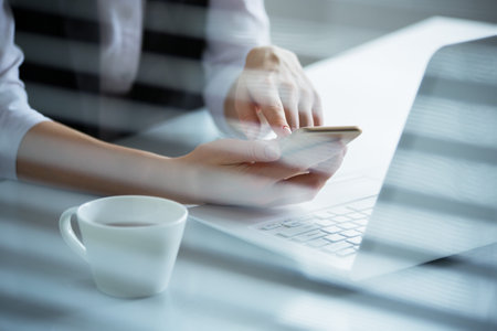 Business woman holding phone and using laptop. Online payment