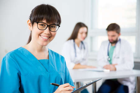 Portrait of a young female doctor in a clinic with colleagues on the backgroundの写真素材