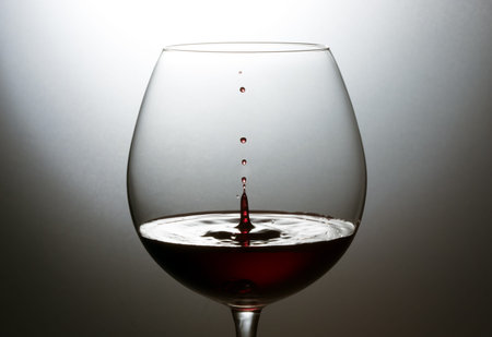 Drop of red wine in a glass on a dark background