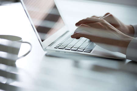 Close-up of hands of business man typing on a laptop. View through blindsの写真素材