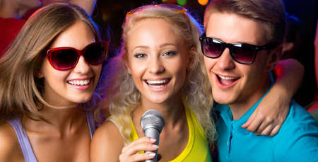 Young people singing into microphone at a partyの写真素材