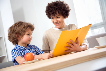 Happy young woman and young boy reading a book
