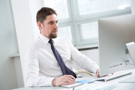 Young handsome businessman working with computer at office