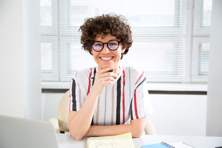 Portrait of pretty business woman looking at camera at workplace in an office