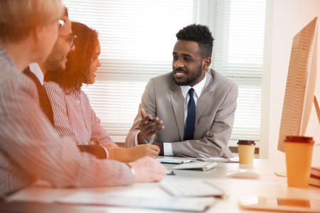 Multy-ethnic group of business people sitting at the office desk and working with computerの写真素材