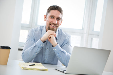 Happy young handsome businessman smiling while looking at camera in office