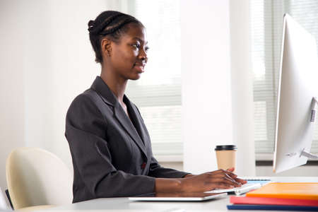 Portrait of pretty african-american business woman looking at camera at workplace in an officeの写真素材