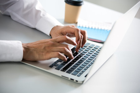 Closeup of businessman's hands working with laptop in an office