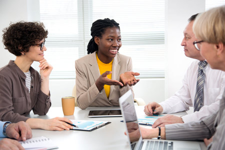 International group of business people working and communicating sitting near office desk together.