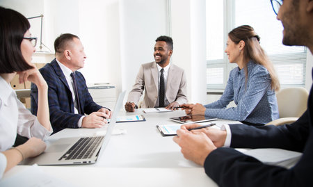 International group of business people working and communicating sitting near office desk together.