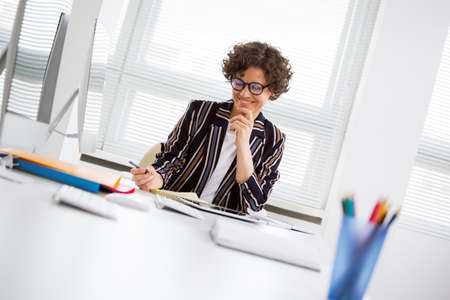 Portrait of a pretty business woman at workplace in officeの写真素材