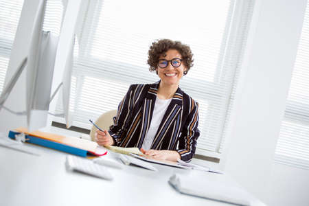 Portrait of a pretty business woman smiling at camera at workplace in an officeの写真素材