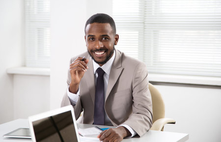 Happy young handsome african american businessman smiling while looking at camera in office