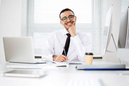 Happy handsome arab businessman smiling while looking at camera in officeの写真素材