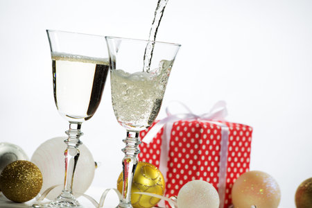 Beautiful splash of champagne glasses and Christmas gifts and balls on a white backgroundの写真素材