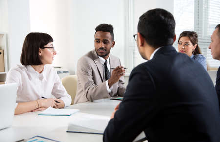 Group of business people sitting around the office desk and discussing the project togetherの写真素材