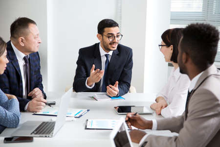 Group of business people sitting around the office desk and discussing the project togetherの写真素材
