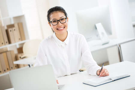Asian business woman smiling at camera at workplace in an officeの写真素材