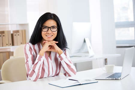 Portrait of a pretty business woman woman with glasses at workplace in officeの写真素材