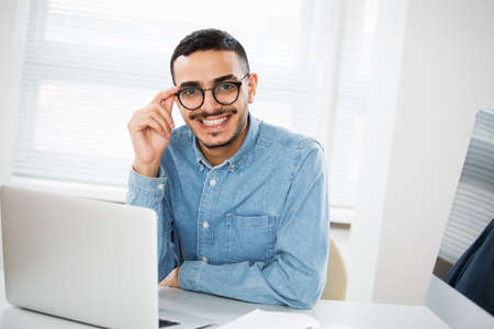 Happy handsome arab businessman smiling while looking at camera in officeの写真素材